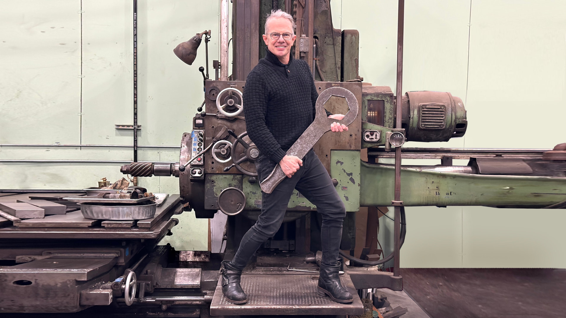 Christopher Hoffmann in the machine shop holding an oversized wrench